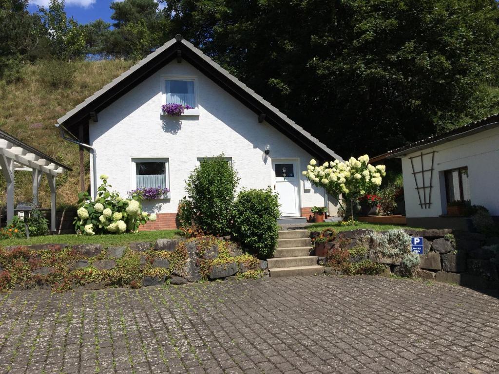 a white house with flowers on the windows and stairs at Jakobs Hütte in Bad Berleburg