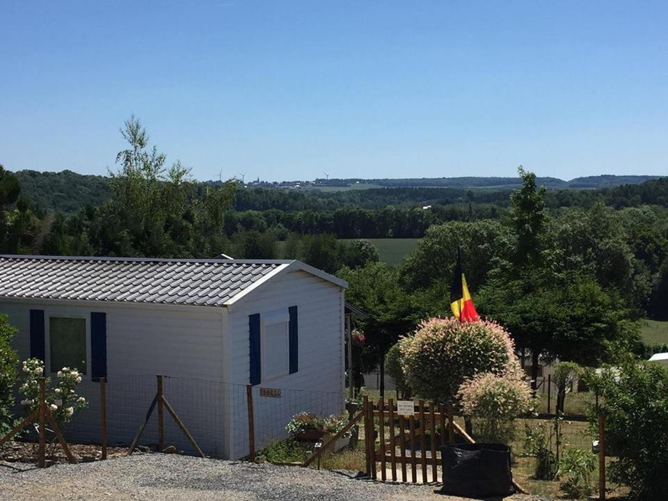 een kleine witte schuur met een vlag erop bij Camping Le pommier rustique in Yvoir