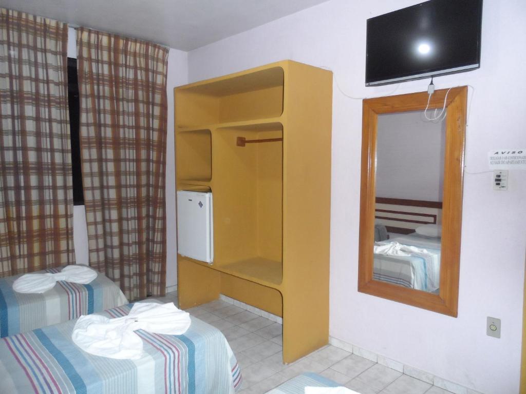 um pequeno quarto com 2 camas e um espelho em Pousada Ilheus em Ilhéus