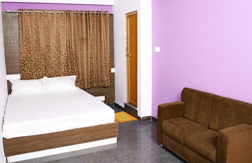 a bedroom with a bed and a couch at Sapphire Inn in Bangalore