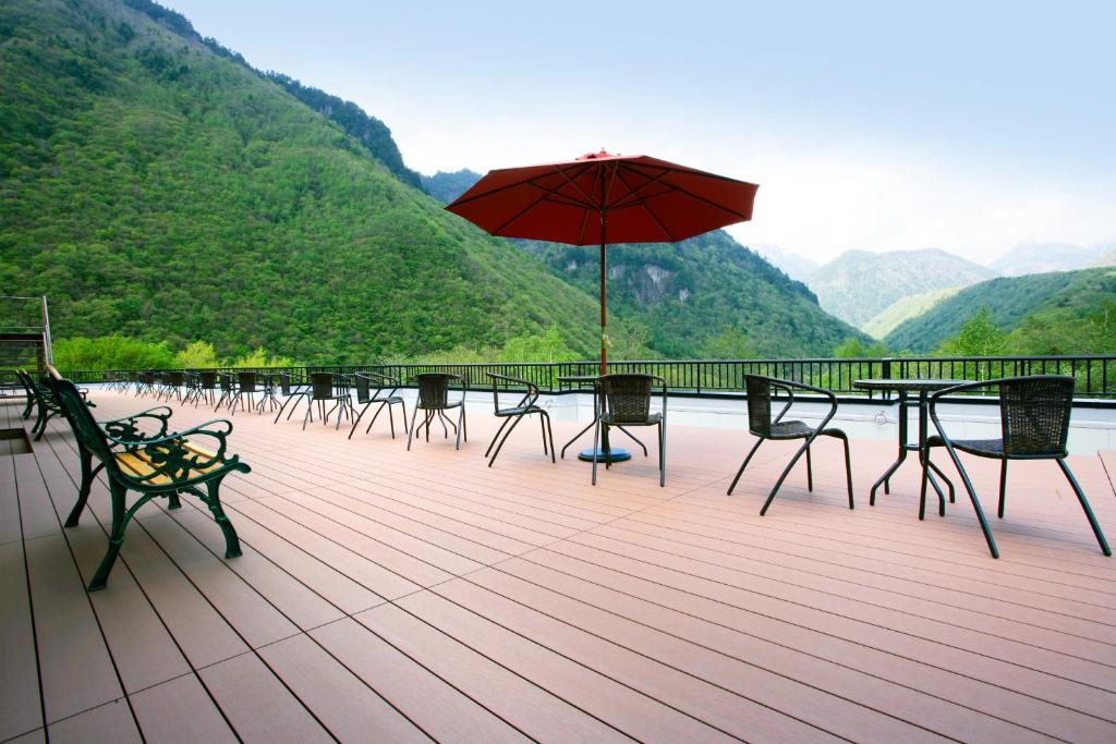 una terraza con mesas, sillas y sombrilla en Nakao Kogen Hotel Kazaguruma, en Takayama