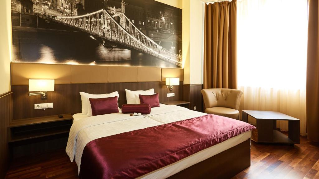 una habitación de hotel con una cama y una foto de un puente en 12 Revay Hotel, en Budapest