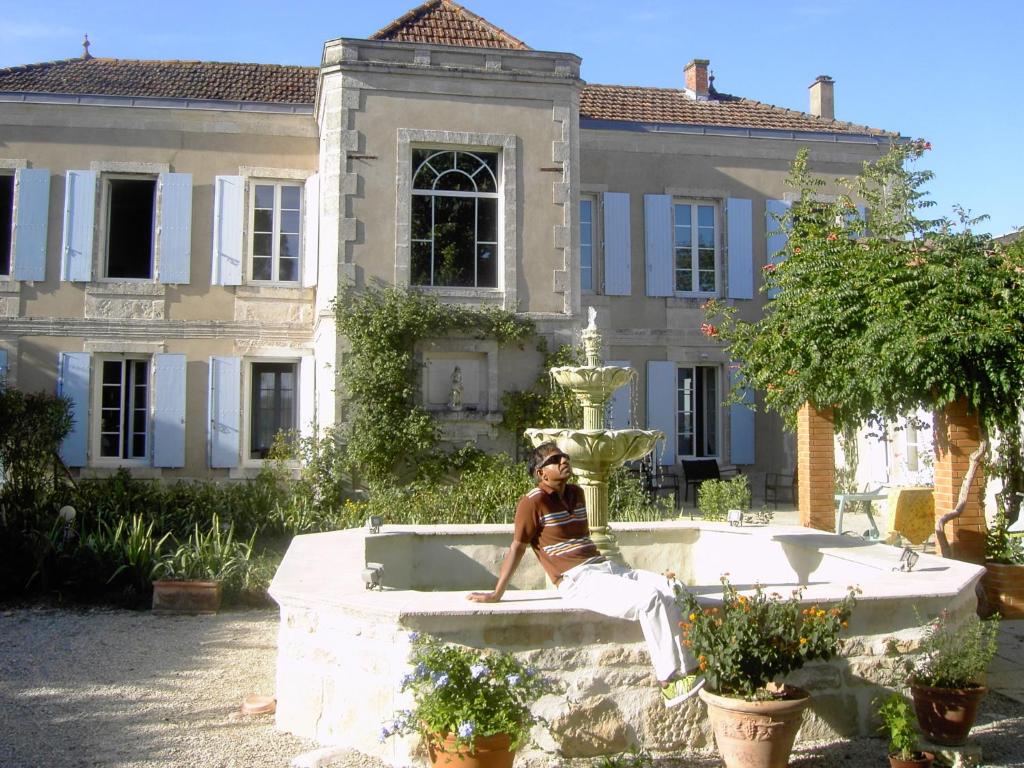 a man sitting on a fountain in front of a house at L'Isle de Bourbon in Le Gué-de-Velluire