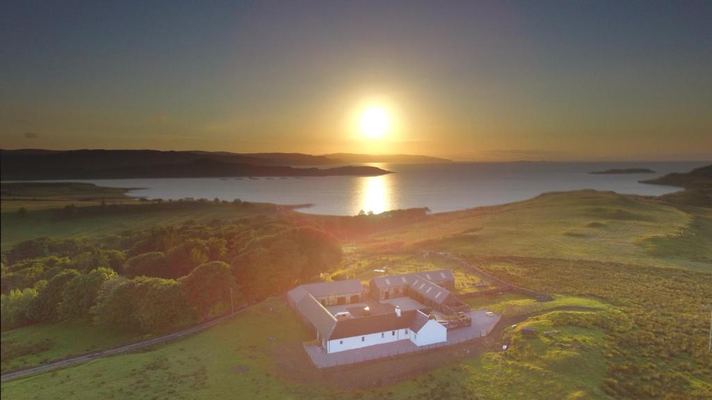 ein Haus auf einem Hügel mit Sonnenuntergang im Hintergrund in der Unterkunft Cottages Lyndale Farm in Flashader