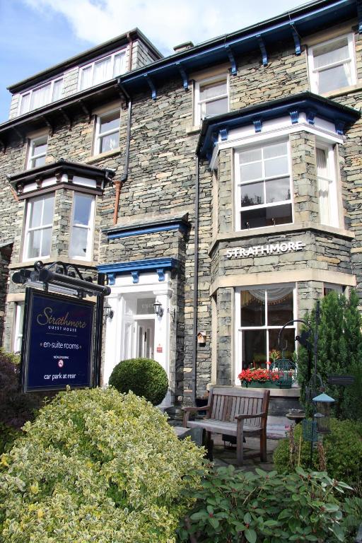 a stone house with a bench in front of it at Strathmore Guest House in Keswick