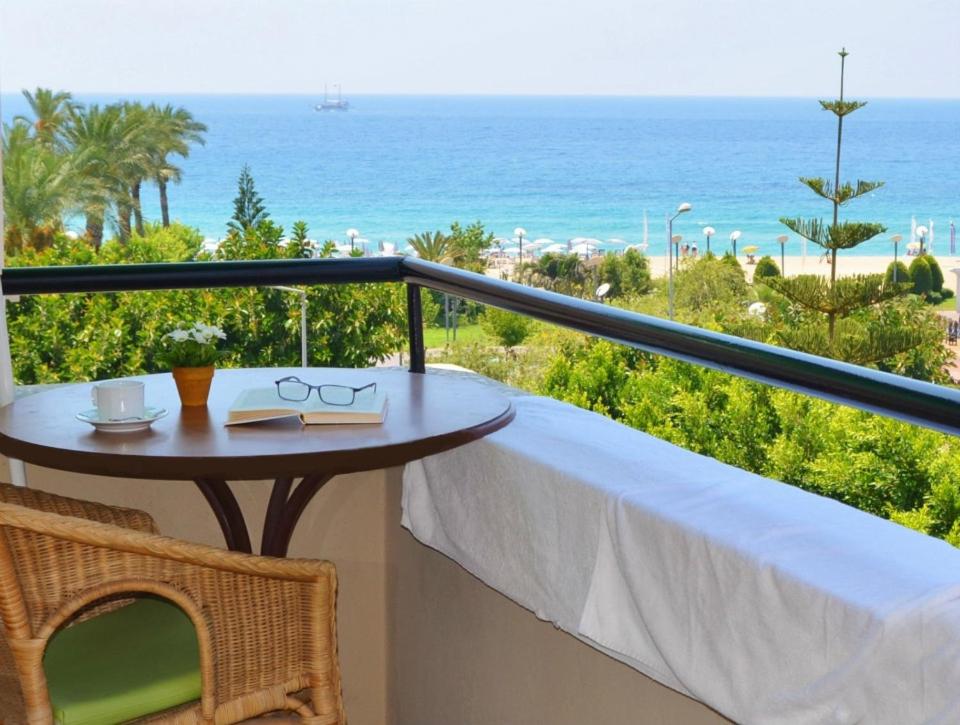 a table on a balcony with a view of the ocean at Kleopatra Carina Hotel in Alanya