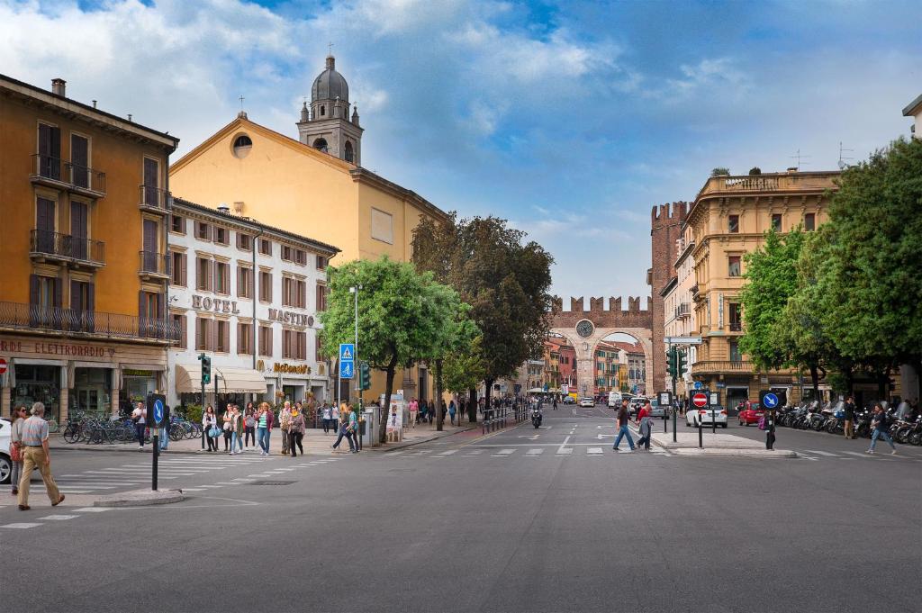 eine belebte Stadtstraße mit Leuten, die die Straße überqueren in der Unterkunft Hotel Mastino in Verona
