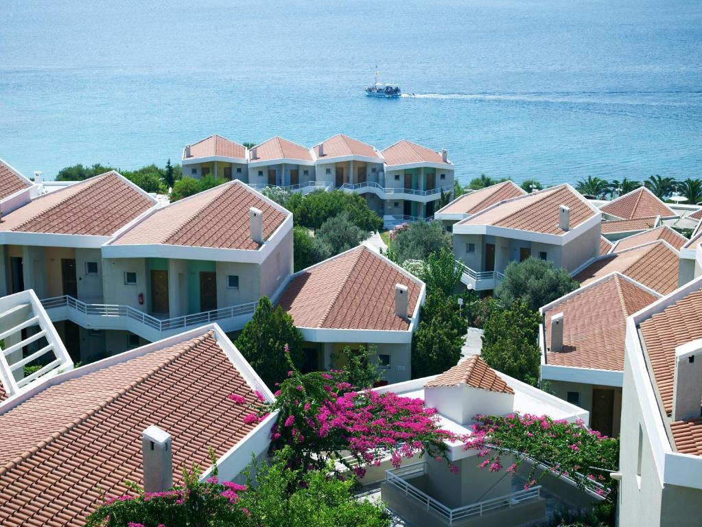 a row of houses with a boat in the water at Proteas Blu Resort in Pythagoreio