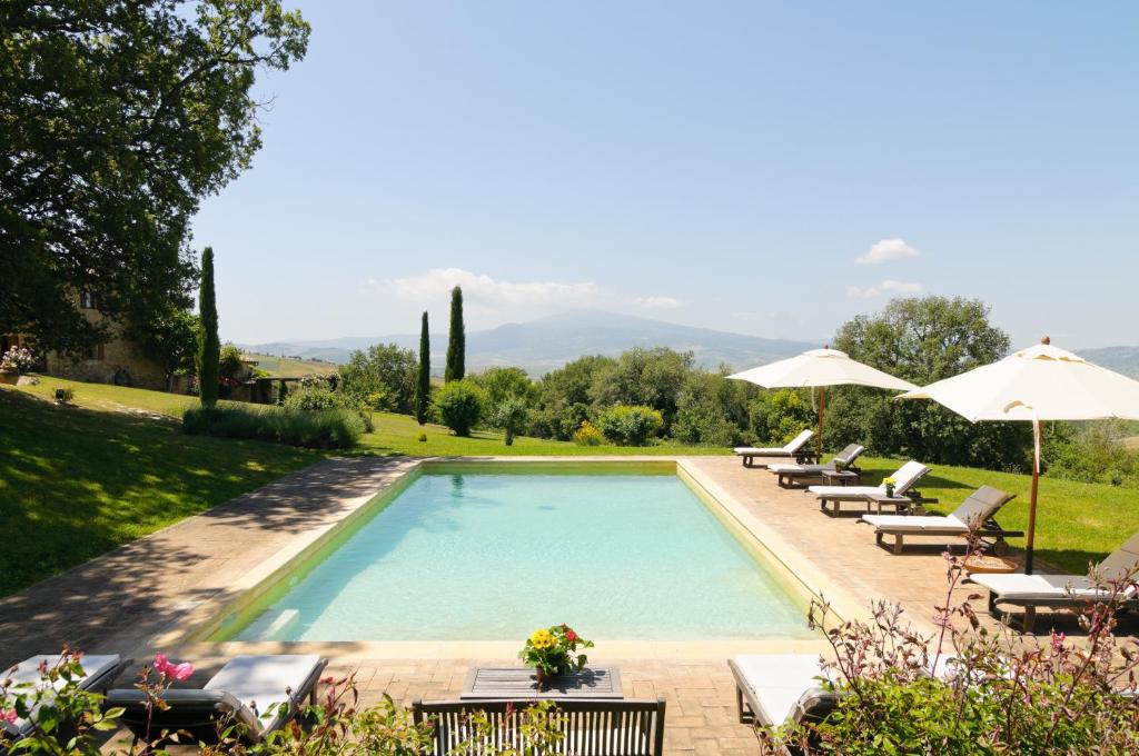 a swimming pool with lounge chairs and umbrellas at Agriturismo Le Macchie in Monticchiello