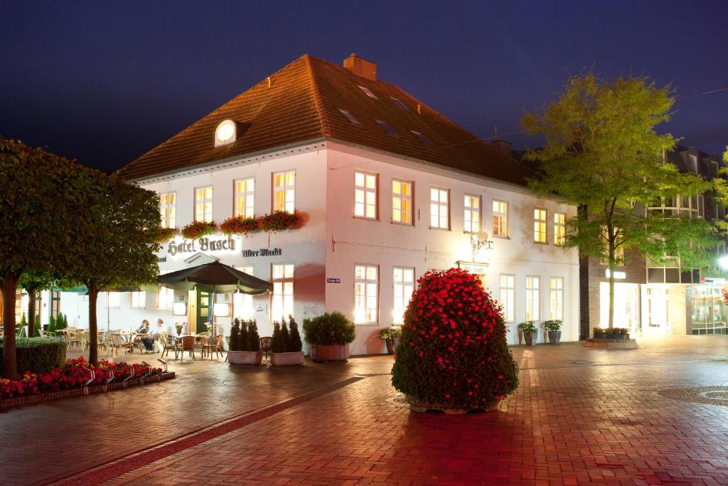 un gran edificio con un gran arbusto delante de él en Hotel Busch, en Westerstede