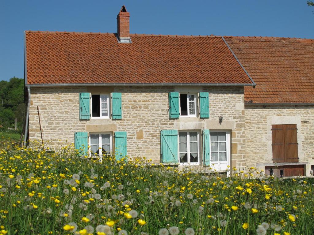 a house with green shutters and a field of flowers at Dans l'Air du Temps in Flagey