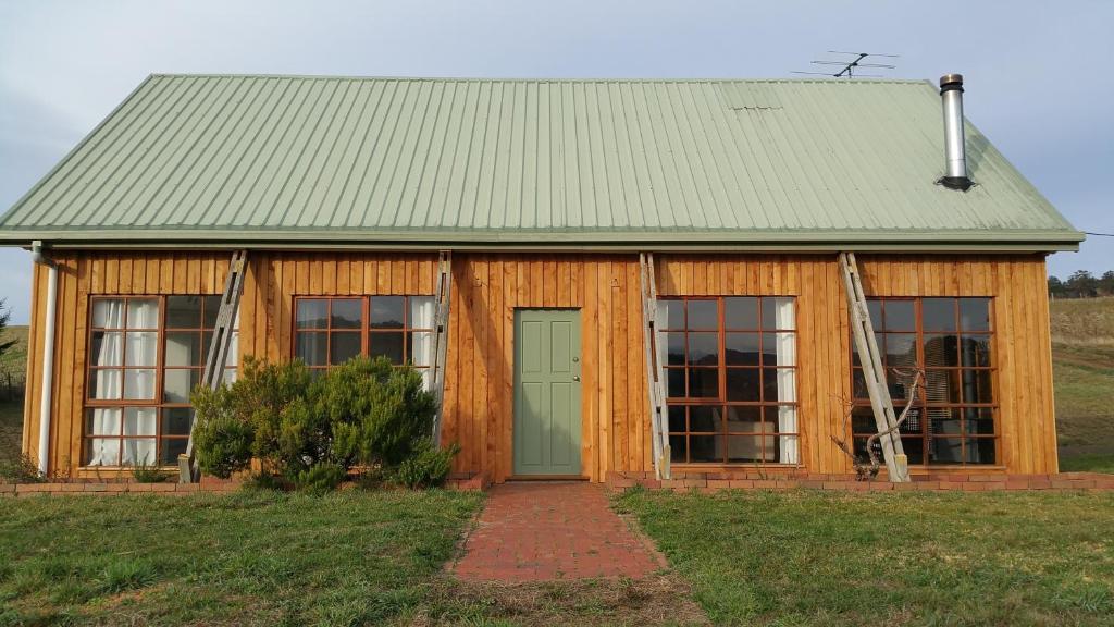a wooden building with a green door and windows at Charles Reuben Estate in Hobart