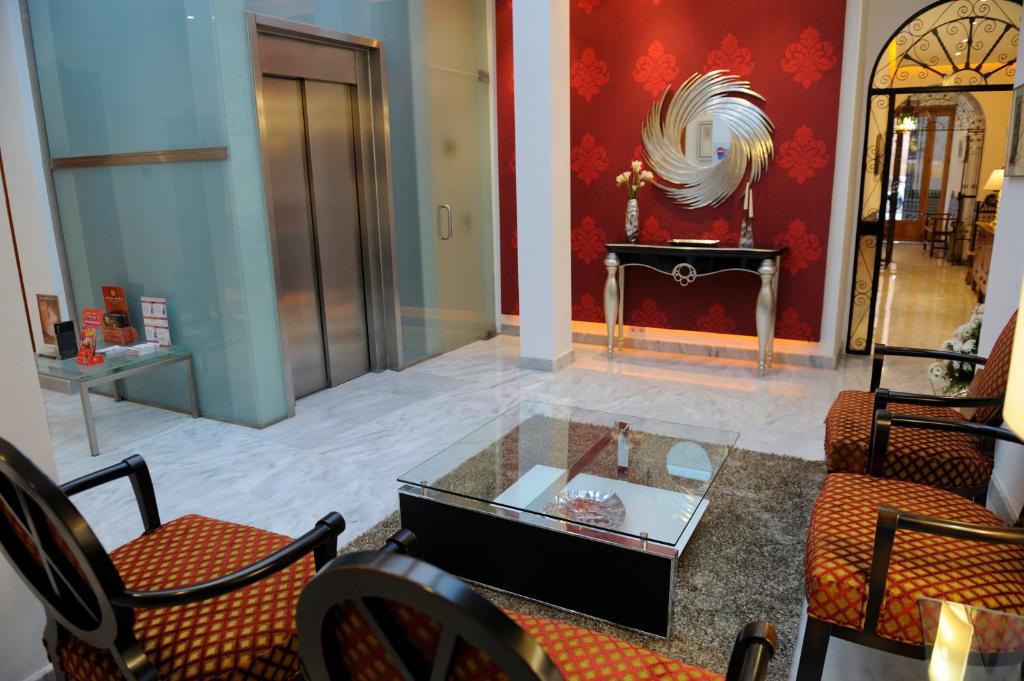 Hotel Goya في إشبيلية: غرفة معيشة مع طاولة وكراسي زجاجية