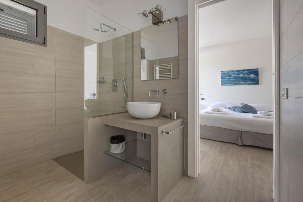 łazienka z umywalką, lustrem i łóżkiem w obiekcie Villa Sogno Bianco by BarbarHouse w mieście Ostuni