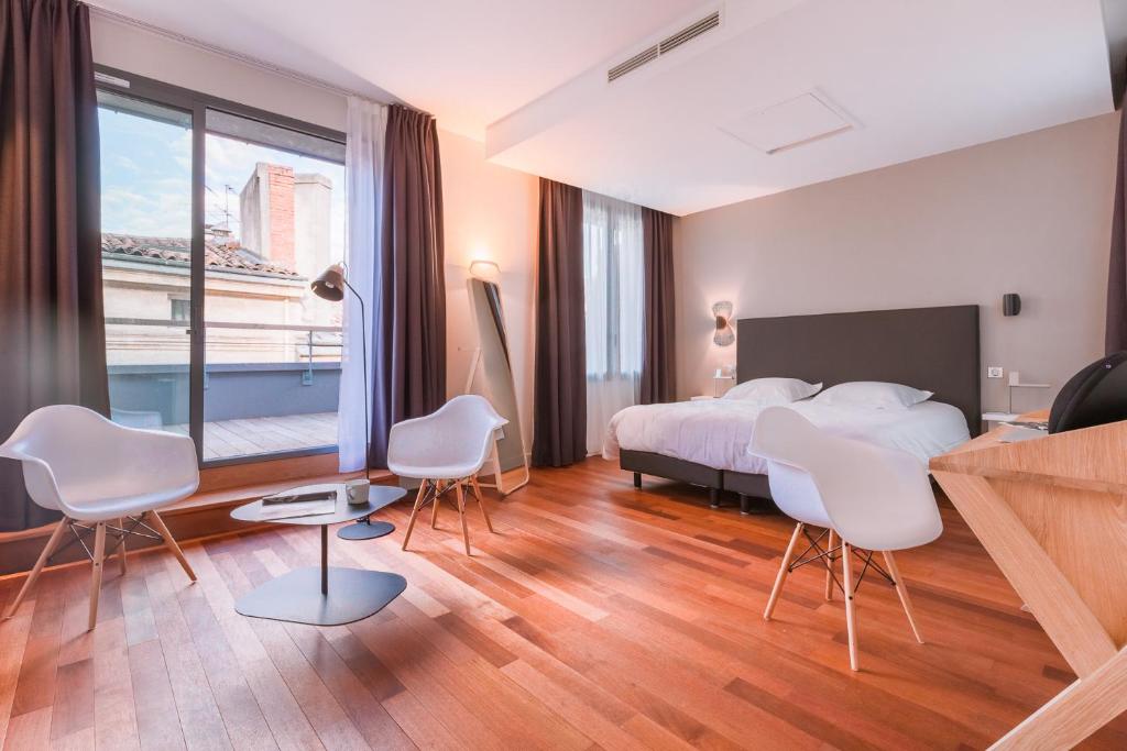 une chambre avec un lit et des chaises et une grande fenêtre dans l'établissement LOFT luxe hyper centre: terrasse/piscine/ salle de sport, à Bordeaux