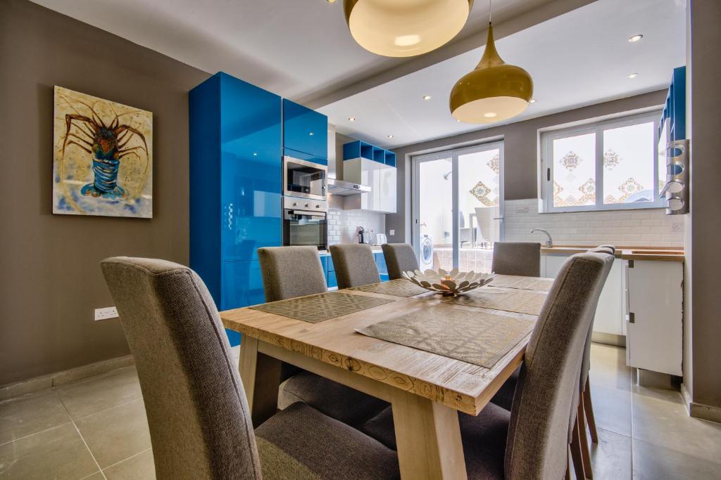 kuchnia i jadalnia z drewnianym stołem i krzesłami w obiekcie Amazing 4-bedroom Sliema Town House with Jacuzzi w mieście Sliema