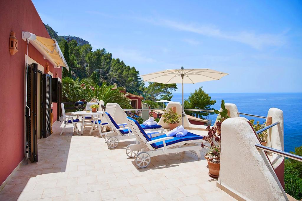 eine Terrasse mit Stühlen, einem Sonnenschirm und dem Meer in der Unterkunft Las Escaleras - Villa DEKA - 2S in Port d’Andratx