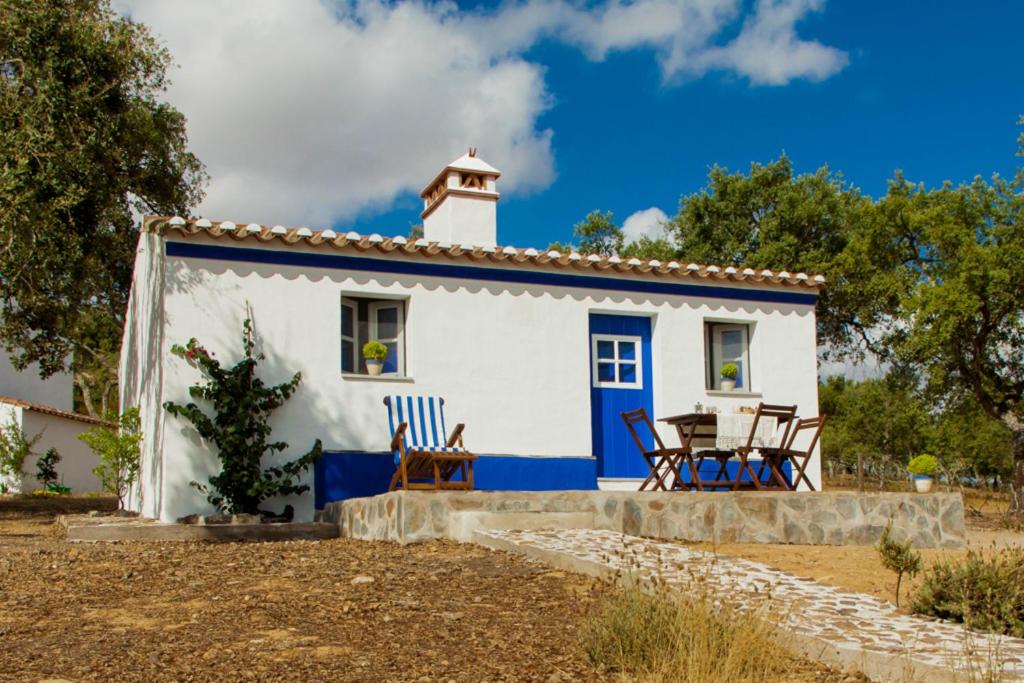 a small white and blue house with chairs and a table at Monte Varandas in Arronches