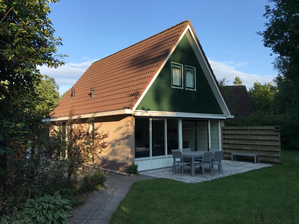 una casa verde con mesa y sillas en el patio en Villa Anna with sauna in Winterswijk, en Winterswijk