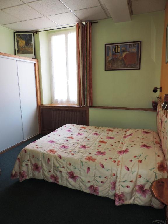 - une chambre dotée d&#39;un lit avec un couvre-lit floral dans l&#39;établissement Hotel De Provence, à Digne-Les-Bains