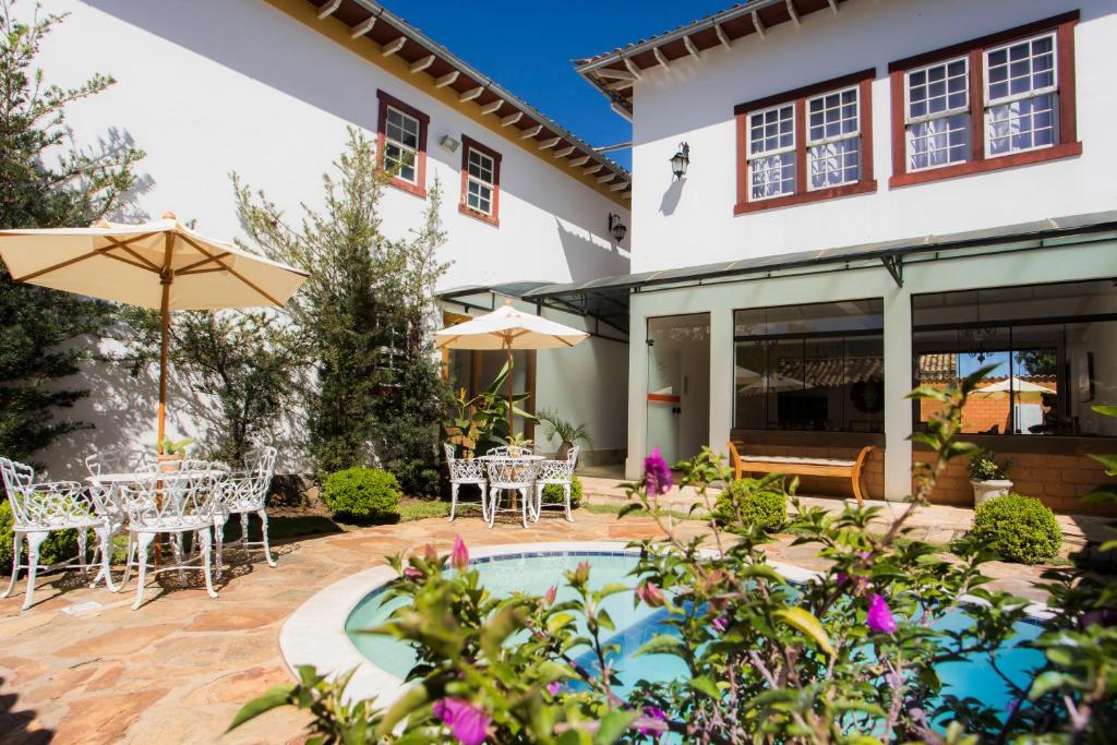 a patio with a table and chairs and an umbrella at Pousada Ouro de Minas in Tiradentes