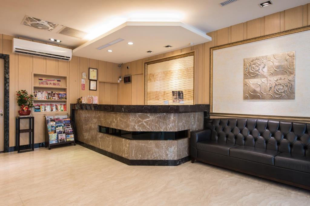 a waiting room with a leather bench and a bar at Hotel South Sea in Kaohsiung