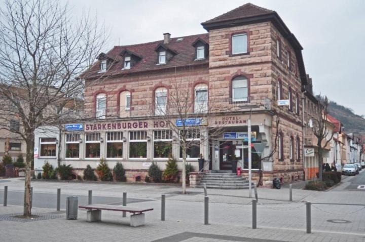 un gran edificio de ladrillo con un banco delante en Hotel Starkenburger Hof en Heppenheim an der Bergstrasse