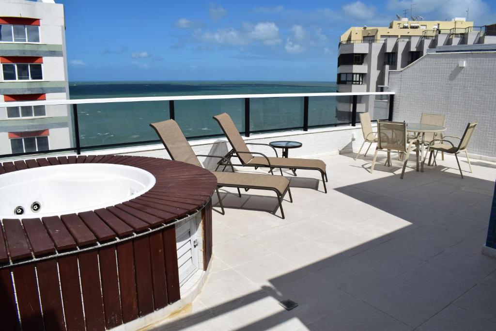 a balcony with chairs and a bath tub on a building at Cobertura Duplex Luxo in Salvador