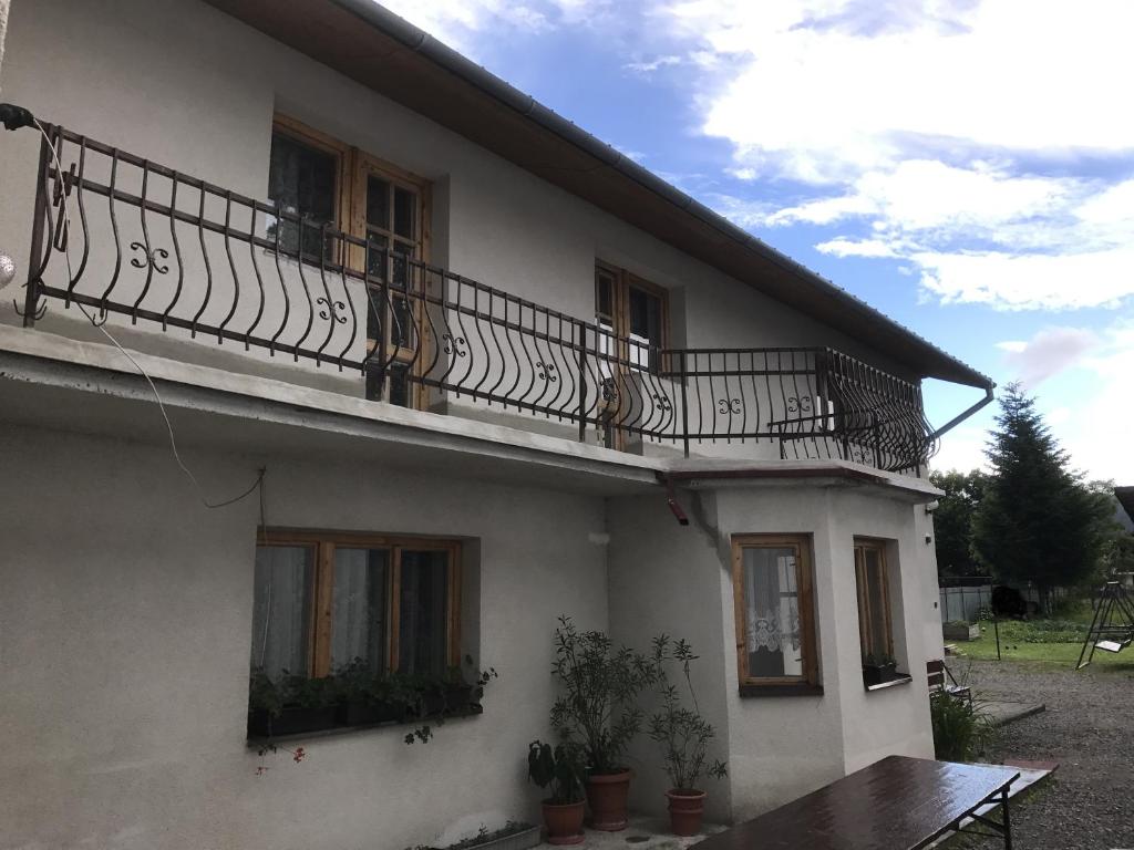 Dieses weiße Haus verfügt über einen Balkon und einen Holztisch. in der Unterkunft Dovolenkový dom s tromi spálňami in Zuberec