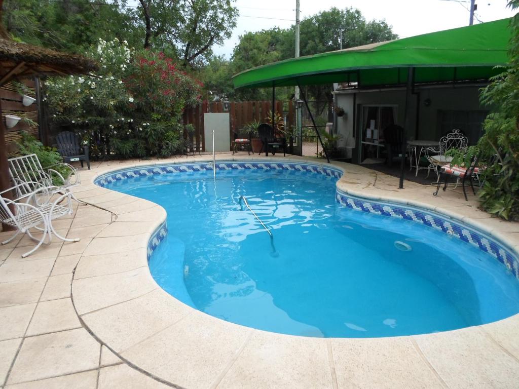 a swimming pool with a patio and a green umbrella at La Casona de Susana in Colón
