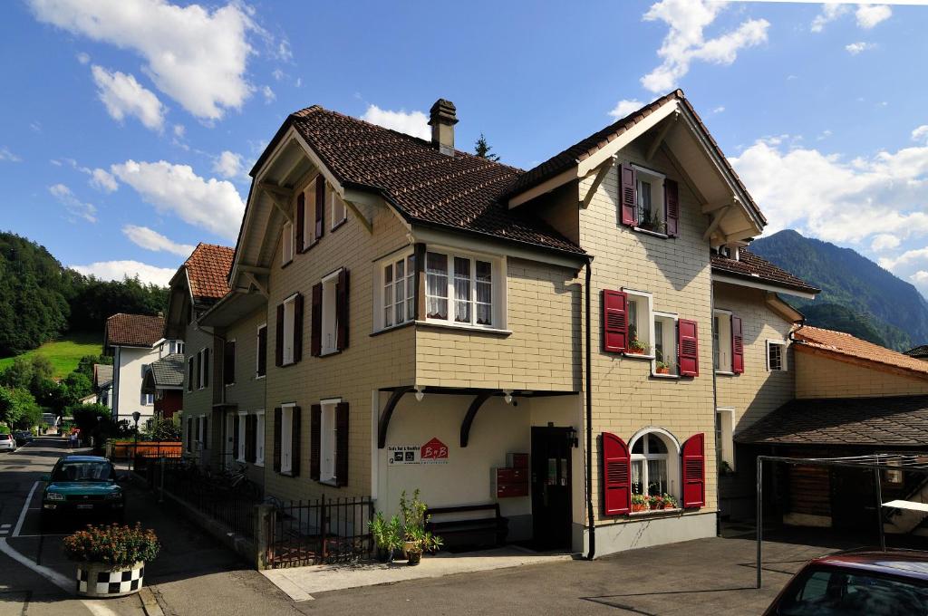 uma casa grande com persianas vermelhas numa rua em Interlaken Apartments em Interlaken