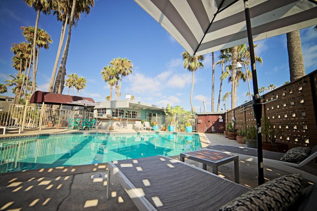 a swimming pool with palm trees and an umbrella at Ocean Villa Inn in San Diego