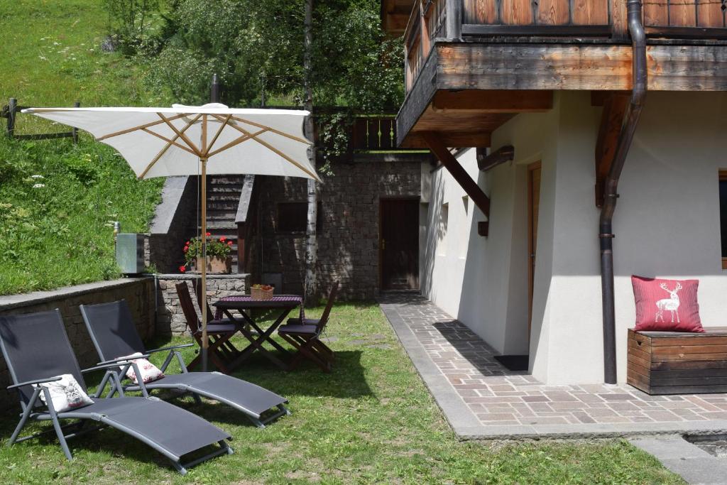 a patio with a table and chairs and an umbrella at Chalet Do Costa in Pozza di Fassa