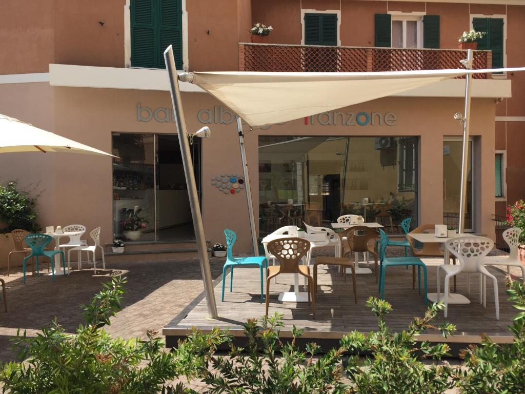 Un patio con mesas y sillas frente a un edificio. en Albergo Franzone, en Tovo San Giacomo