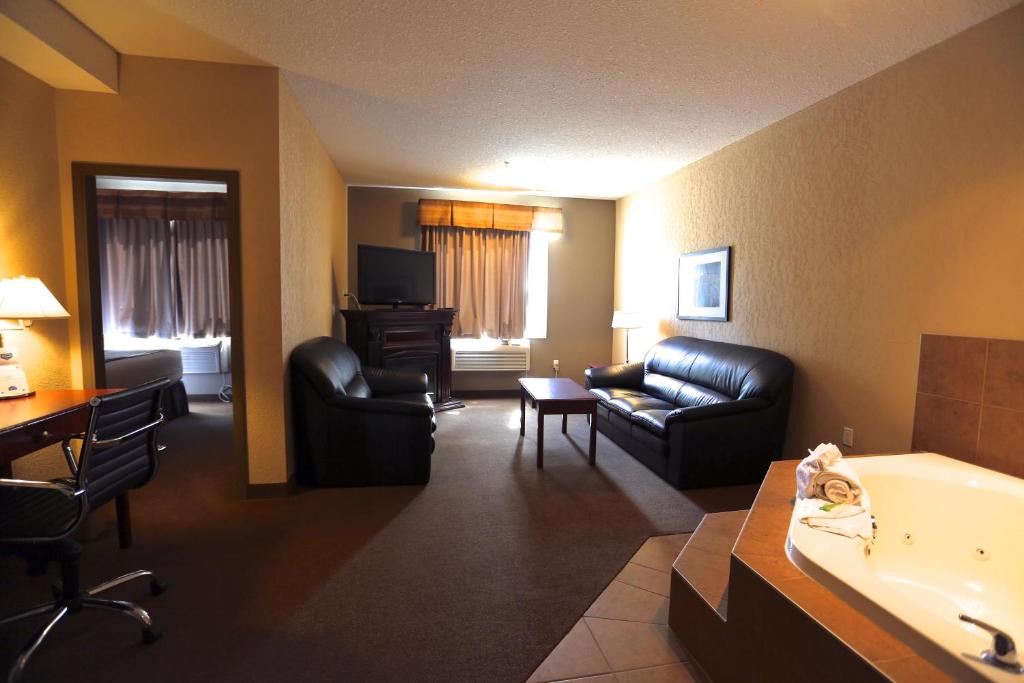 een hotelkamer met een bad en een woonkamer bij Lakeview Inns & Suites - Fort Nelson in Fort Nelson