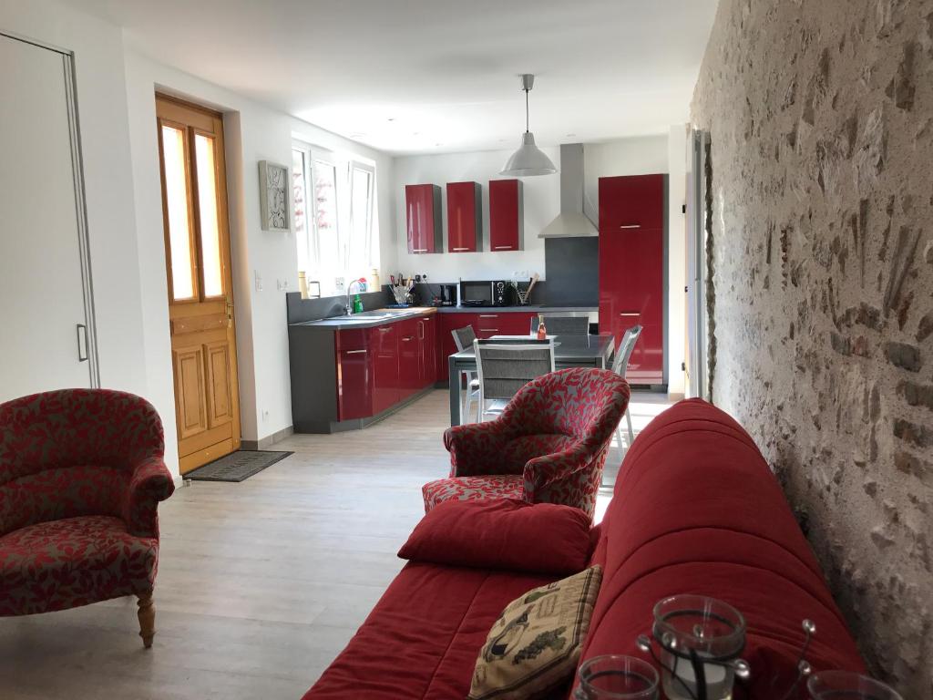 a living room with a red couch and two chairs at Gîte du Parc des Mauves in Meung-sur-Loire