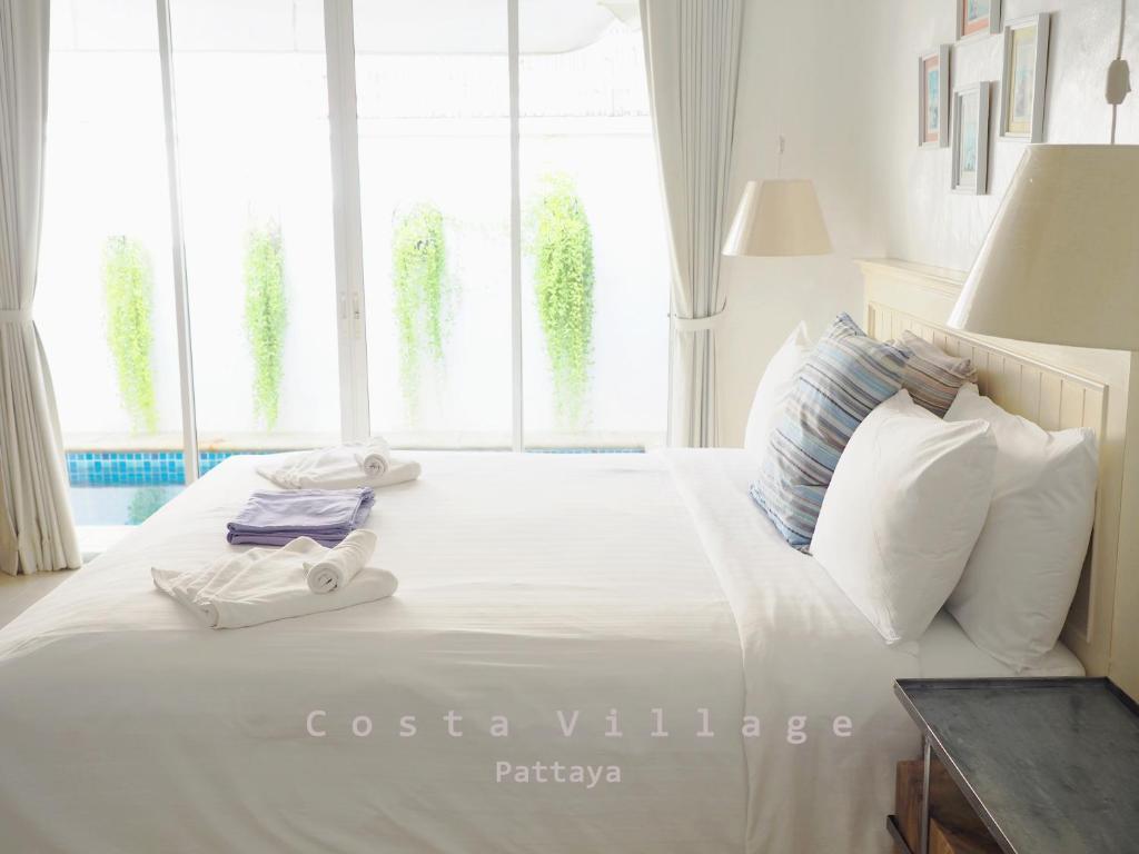 a white bed with white pillows and towels on it at Costa Village Pool Villa in Jomtien Beach
