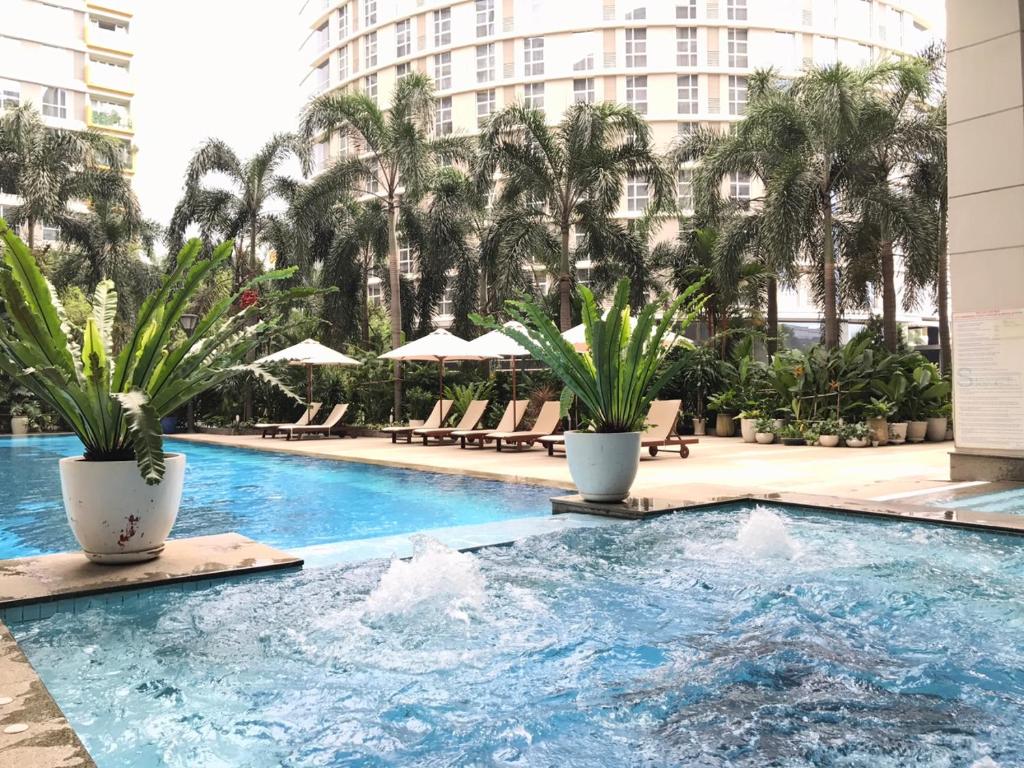 ein Pool mit Palmen und ein Gebäude in der Unterkunft Bluesky Serviced Apartment Airport Plaza in Ho-Chi-Minh-Stadt