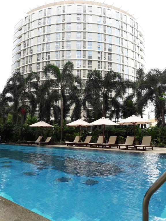 a swimming pool with chairs and a large building at Bluesky Serviced Apartment Airport Plaza in Ho Chi Minh City