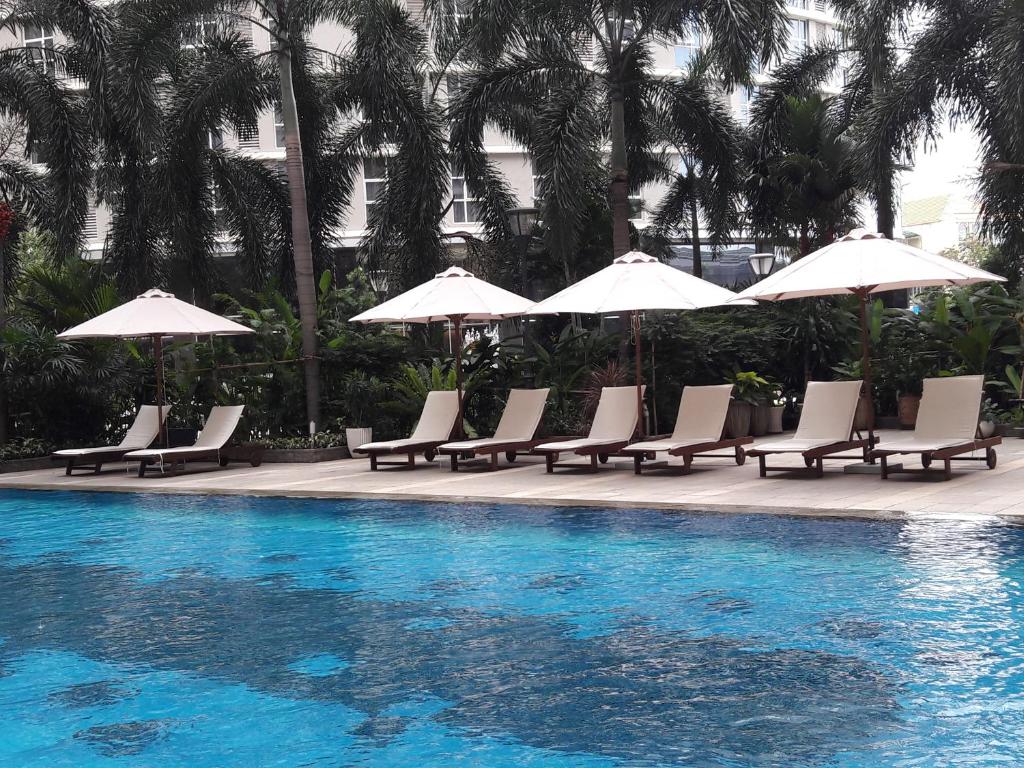 a group of chairs and umbrellas next to a swimming pool at Bluesky Serviced Apartment Airport Plaza in Ho Chi Minh City