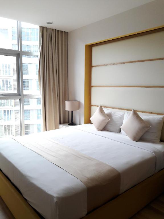 a bedroom with a large white bed with a window at Bluesky Serviced Apartment Airport Plaza in Ho Chi Minh City