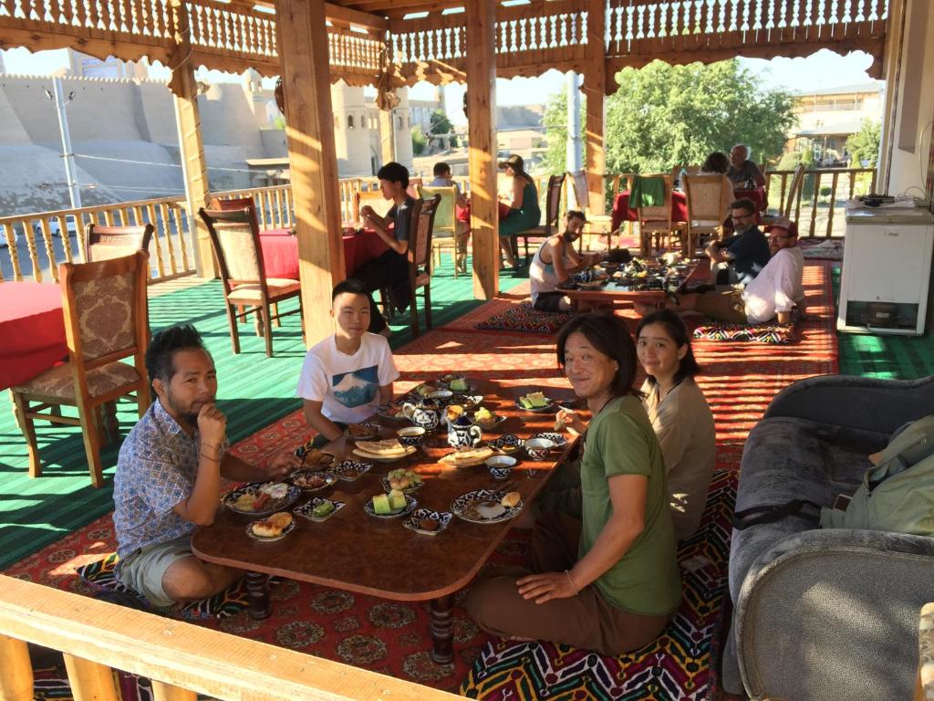 grupa ludzi siedzących przy stole z jedzeniem w obiekcie Khiva Alibek B&B & Travel w mieście Chiwa