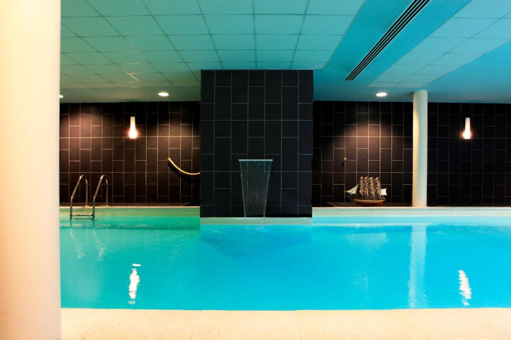 uma piscina com água azul e azulejos pretos em Amiral Hôtel em Paris