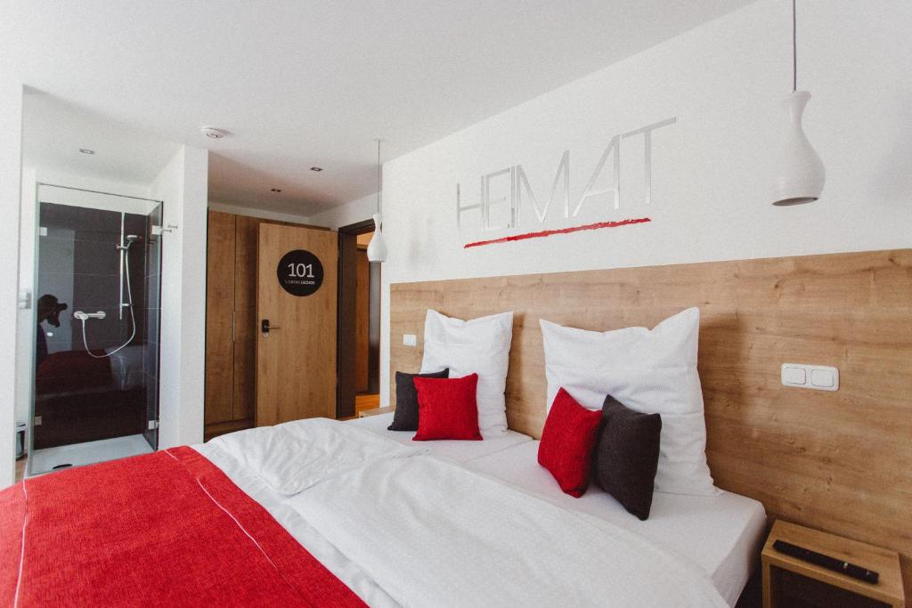 a bedroom with a large bed with red and black pillows at HEIMAT | Hotel & Boarding House in Mainburg