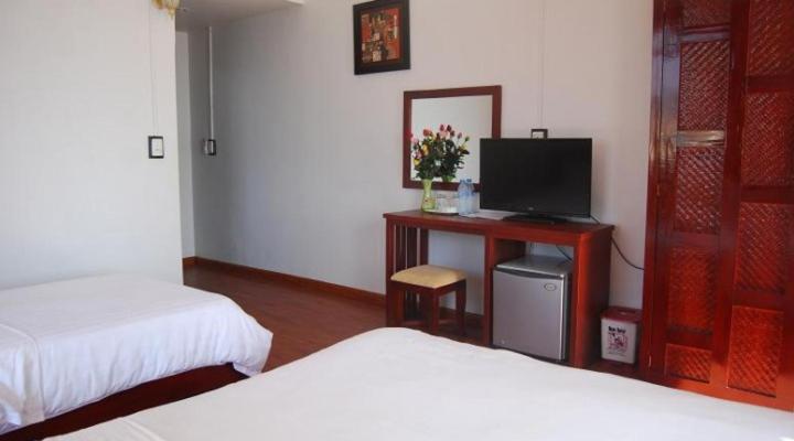 a bedroom with two beds and a tv and a desk at Camellia Guest House in Sapa