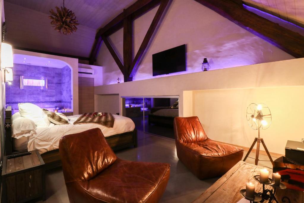 Abri Cosy - Suite Romantique في سان جيل: غرفة نوم بسرير وكرسيين وتلفزيون