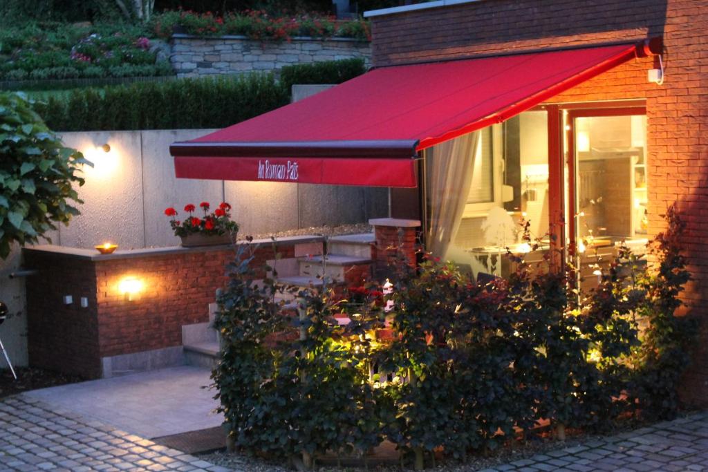 a restaurant with a red awning and some flowers at B&B Au Roman Païs in Braine-le-Château