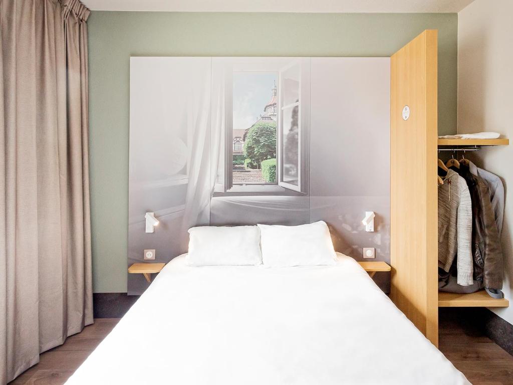 um quarto com uma cama branca e uma janela em B&B HOTEL Mulhouse Centre em Mulhouse