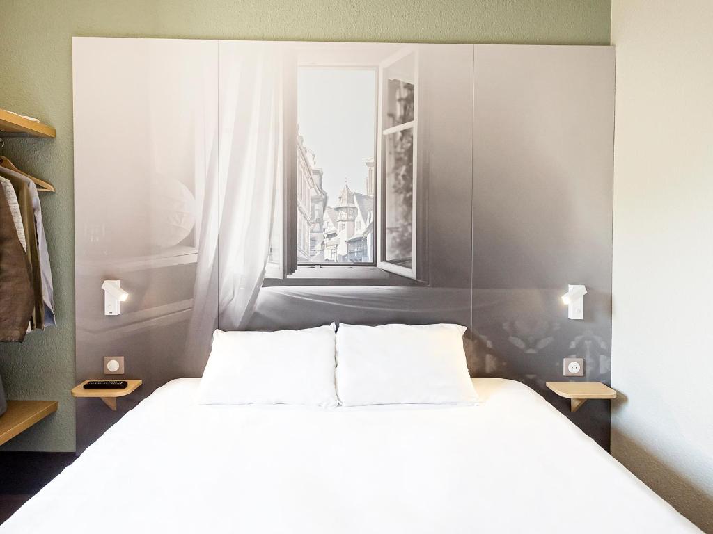 a bedroom with a large bed and a window at B&B HOTEL Colmar Vignobles Ouest in Colmar