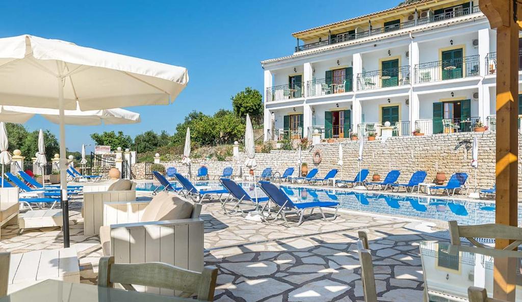 un hotel con sillas, sombrilla y piscina en Captain Spiros Studios en Paleokastritsa